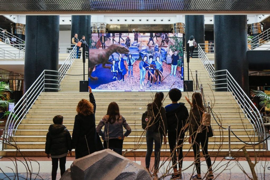 Animation événementielle en centre commercial avec écran interactif attirant les visiteurs dans la galerie marchande