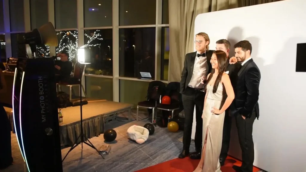 Invités posant devant une borne à selfie avec fond photo et éclairage studio lors d’une soirée événementielle élégante