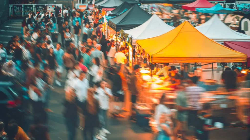 Animation événementielle en espace public lors d’un marché urbain animé rassemblant habitants et visiteurs autour de stands festifs