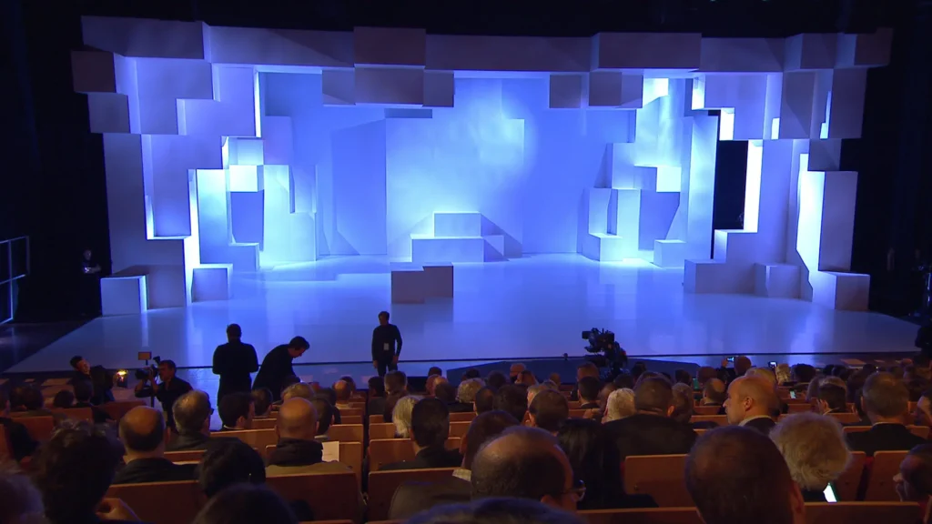 Salle de conférence accueillant un événement d’entreprise avec une scénographie lumineuse et une animation visuelle immersive sur scène