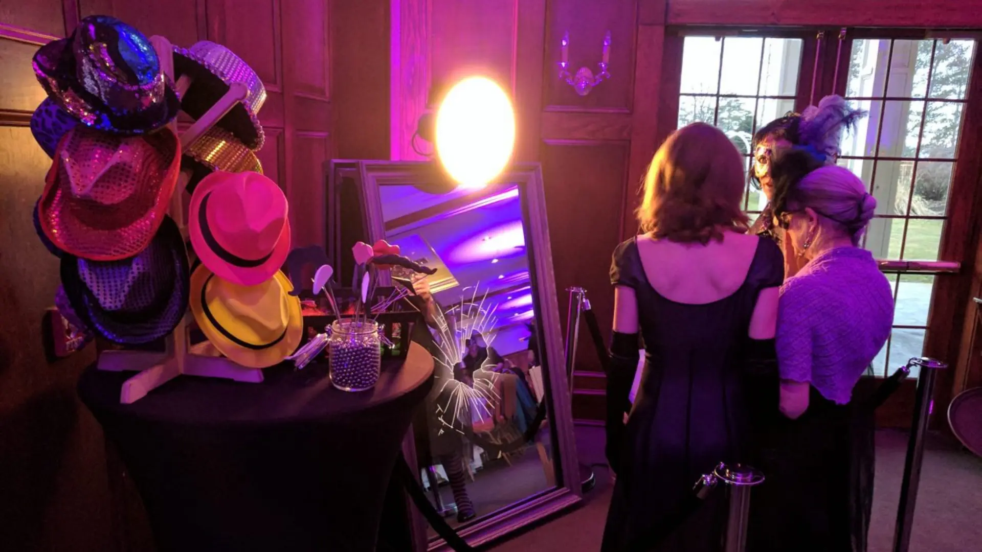 Invités utilisant un miroir photobooth interactif avec accessoires élégants lors d’une soirée événementielle dans un lieu raffiné