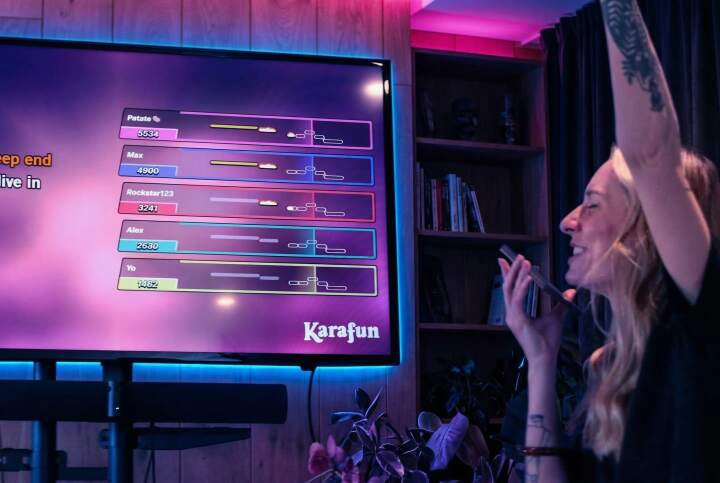 Écran de karaoké affichant le classement des chanteurs en mode battle pendant qu’une participante chante